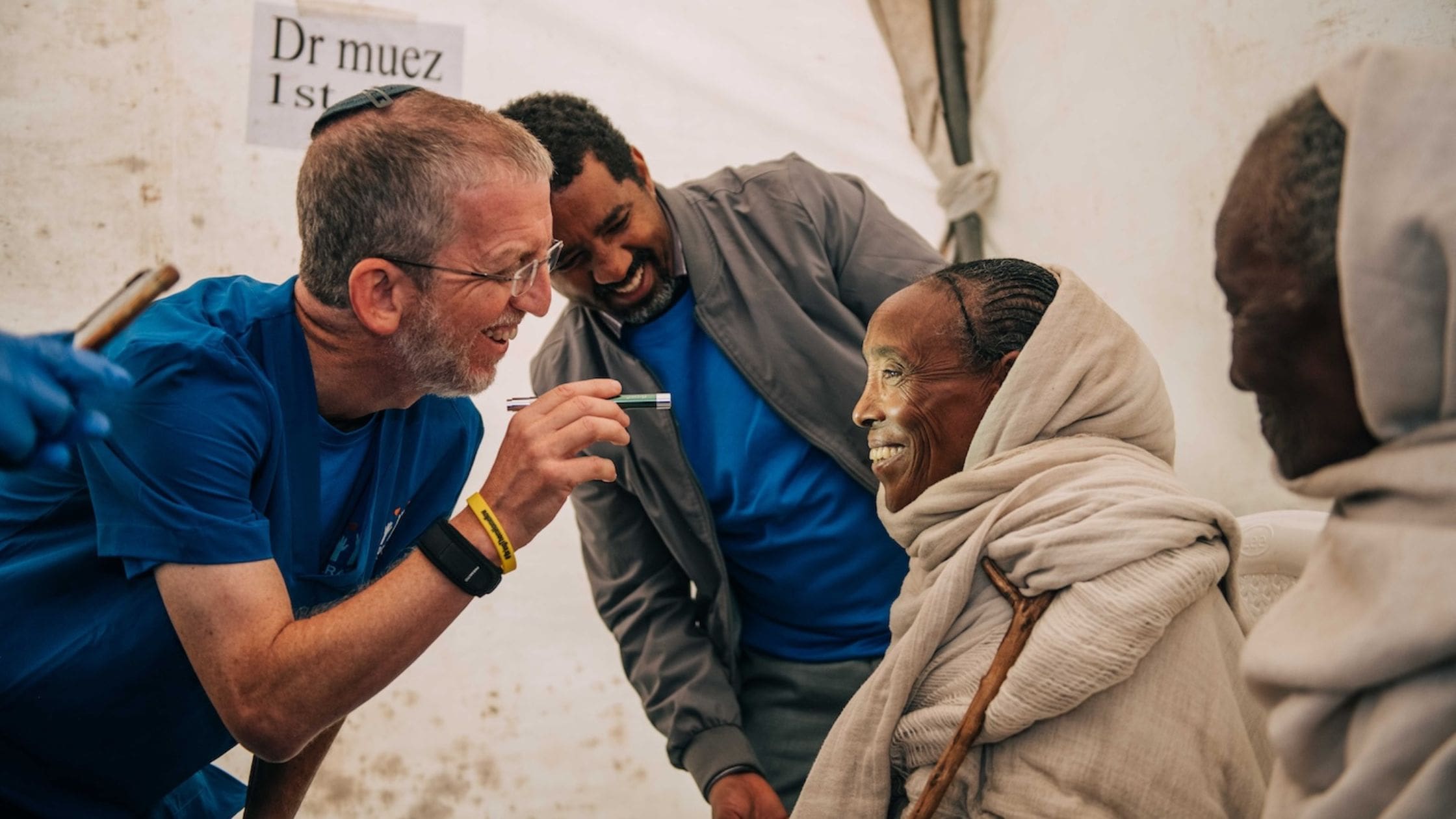 dr. morris hartman doing eye exam on smiling ethiopian woman